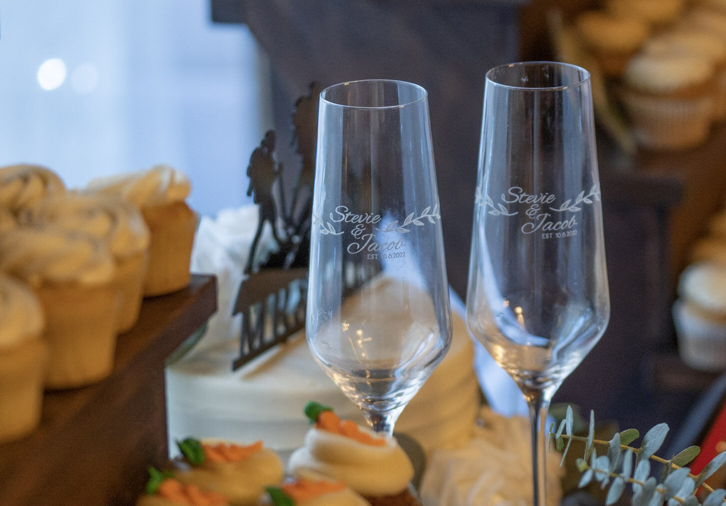 Wedding glasses sitting on a table with custom engraving 
